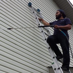 student pressure washing siding