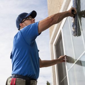 window cleaner washing a window with a shammy